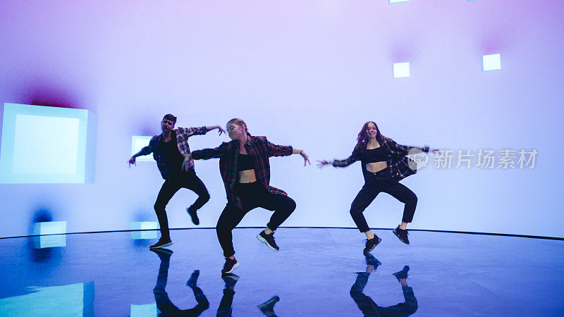 在工作室环境的虚拟制作过程中，三名专业舞蹈家在一个大的Led墙壁屏幕前用VFX动画表演嘻哈舞常规。105 BPM歌曲。